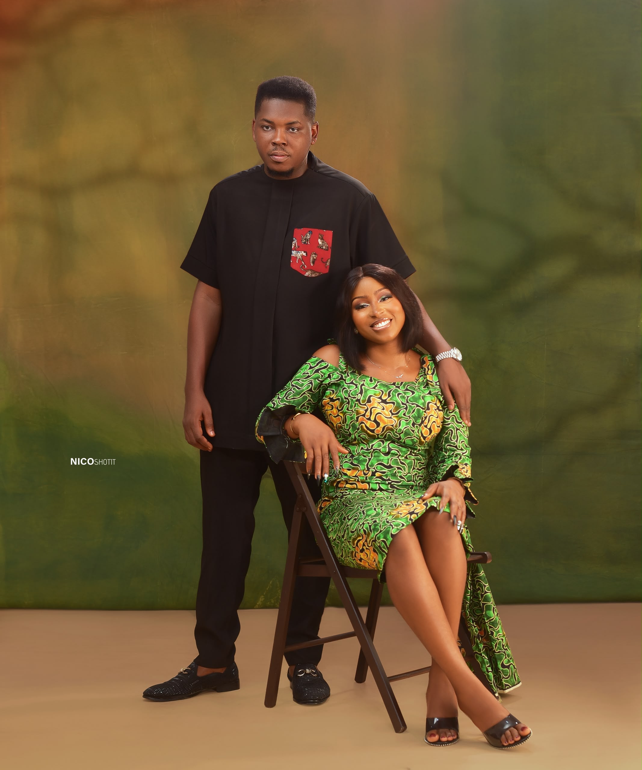 Chisom seated on a chair as Mmachukwu stands gracefully behind him