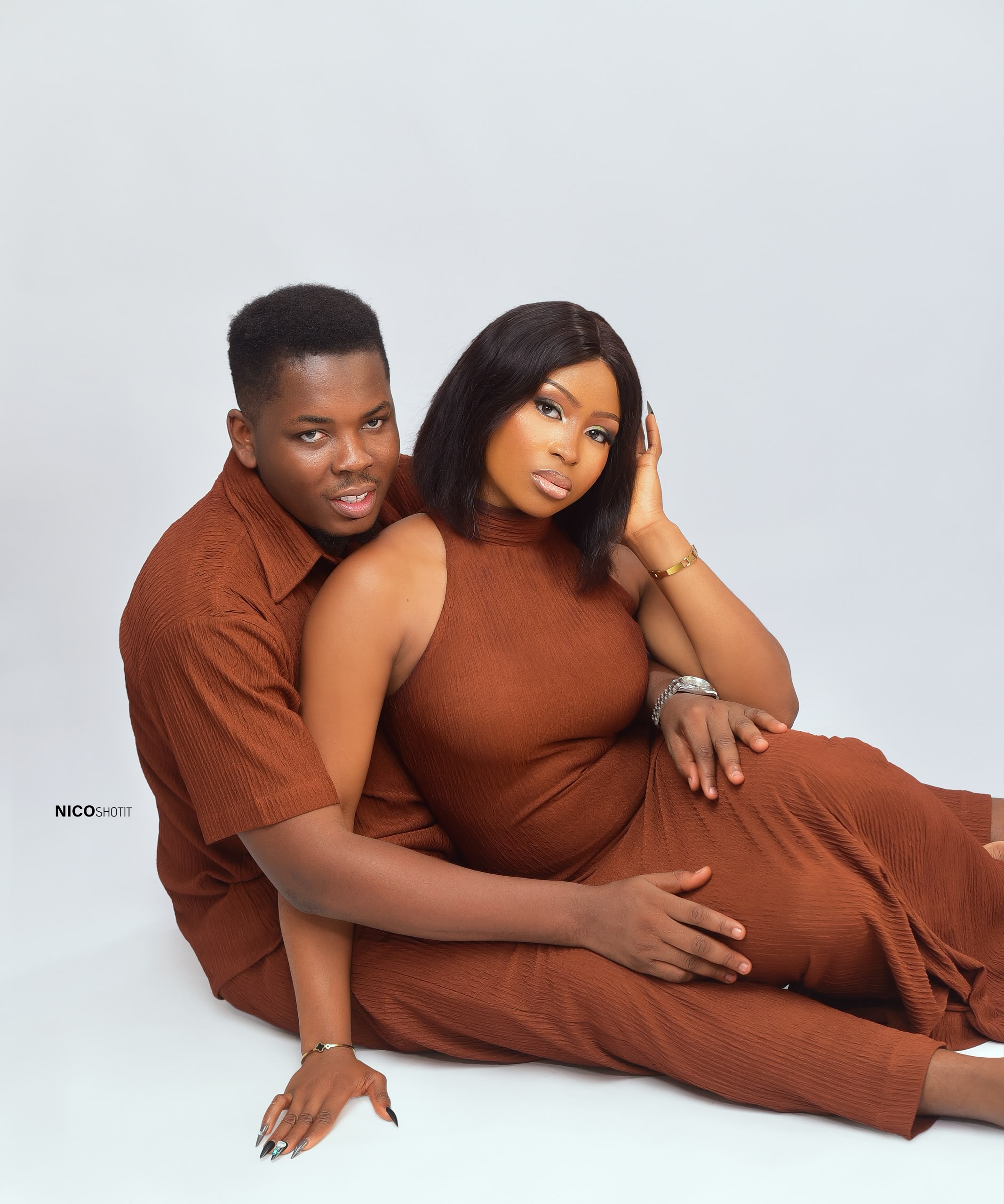 Mmachukwu and Chisom sitting close together in matching earthy rust outfits